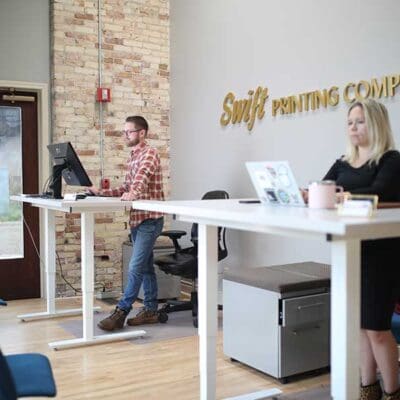 two people in a minimalist standing desk office